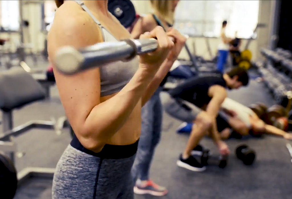 Several people performing a variety of exercises in a gym.
