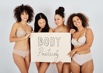 pics for blog article 123123 body positivity Several female models pose with a sign that says Body Positivity