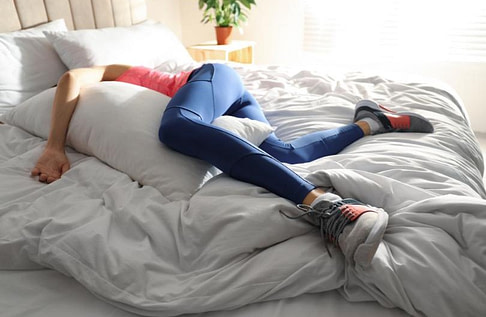 a runner sleeping in bed with running shoes still on
